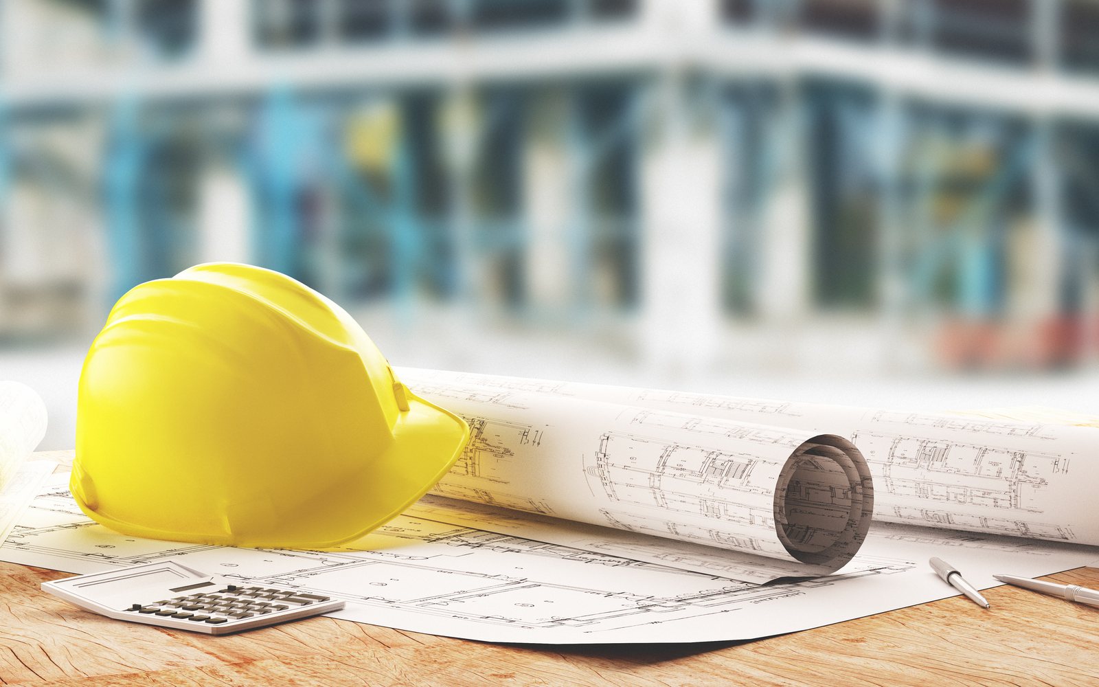 Elmetto da cantiere e disegni tecnici appoggiati su un tavolo da lavoro