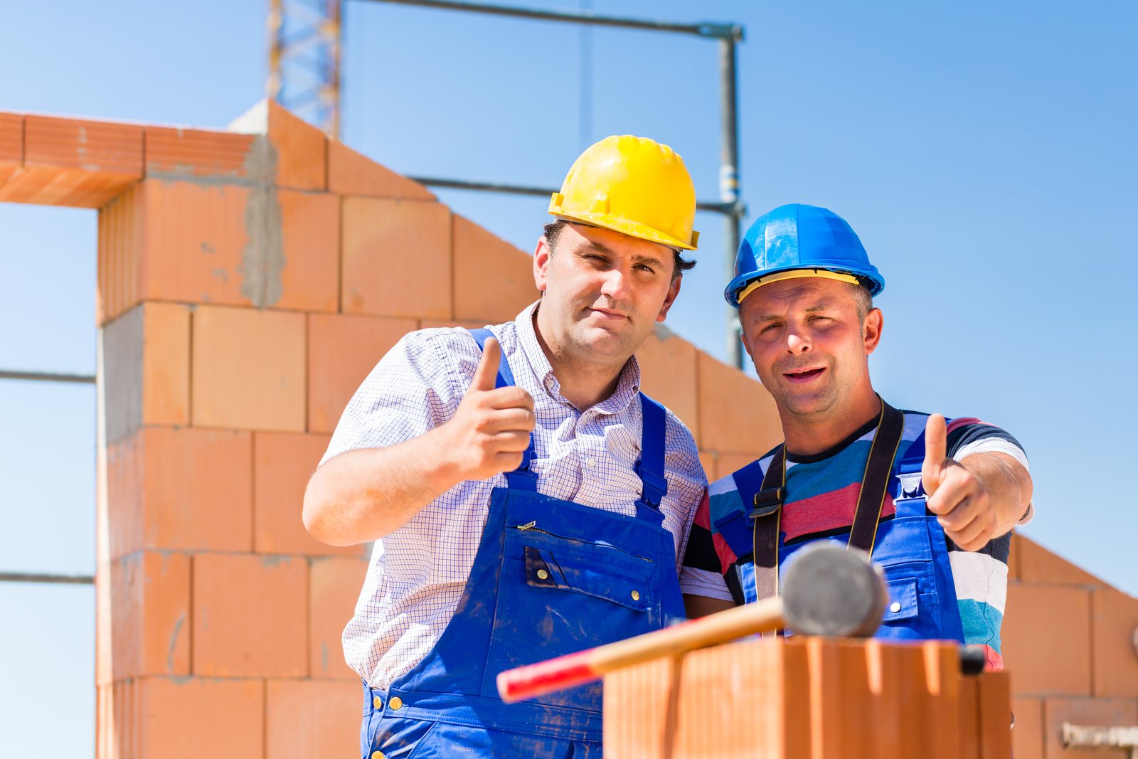 Due operai edili al lavoro sulla muratura di un edificio in costruzione